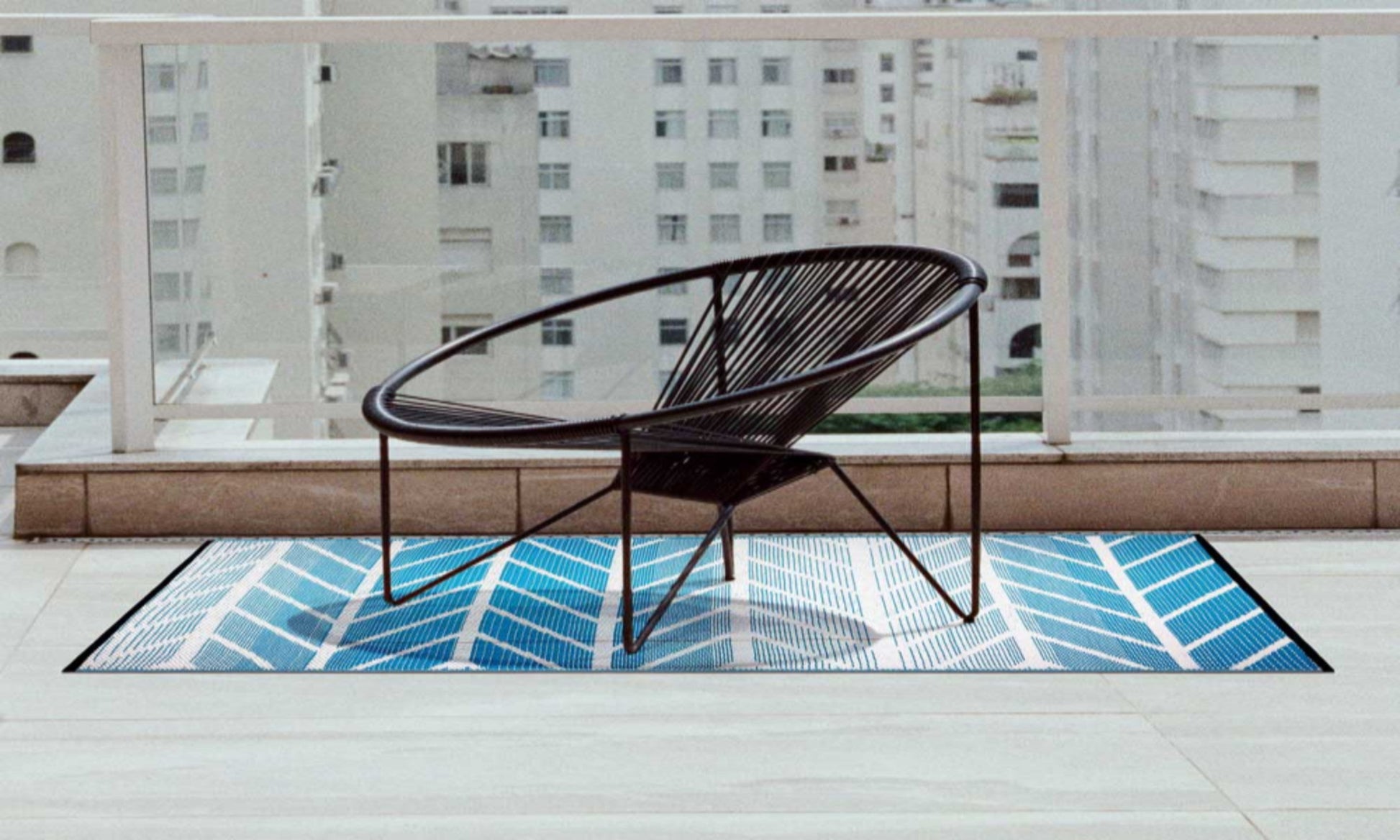 Wicker chair on a balcony with a blue geometric rug