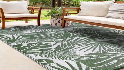 Tropical leaf patterned rug on a patio with wooden chairs and a couch.